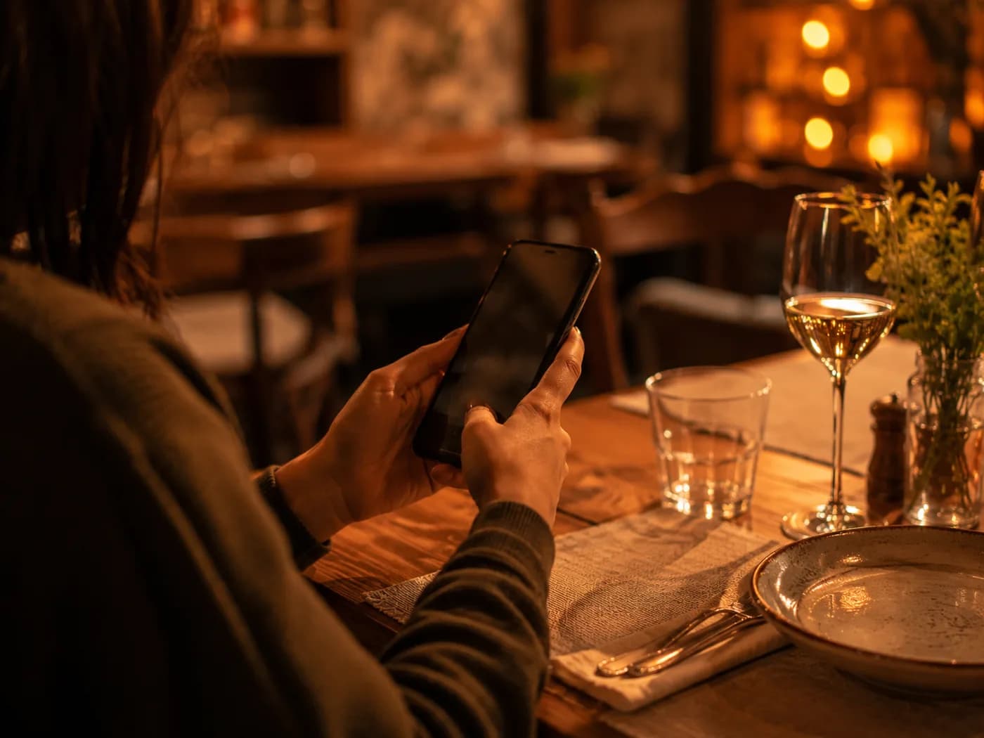 Un cliente con il telefono in mano al tavolo di un ristorante